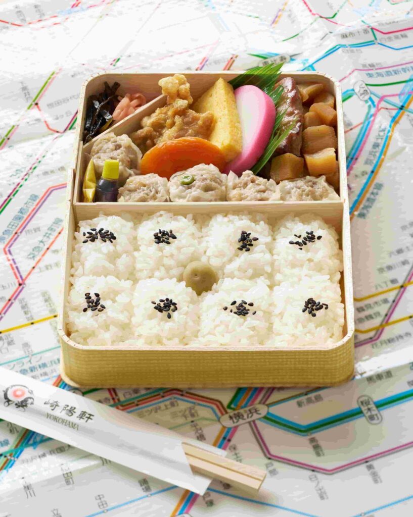 Bento box with rice and an assortment of vegetables and shumai. 